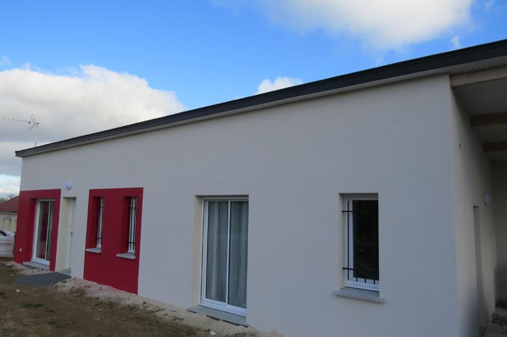 un edificio blanco con puertas rojas. en Chambre chez Marie avec vue imprenable, en Sainte-Feyre