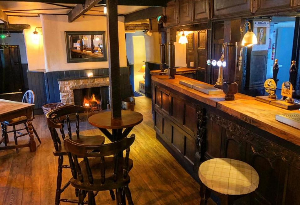 a bar with a fireplace and a table and chairs at String Of Horses in Carlisle