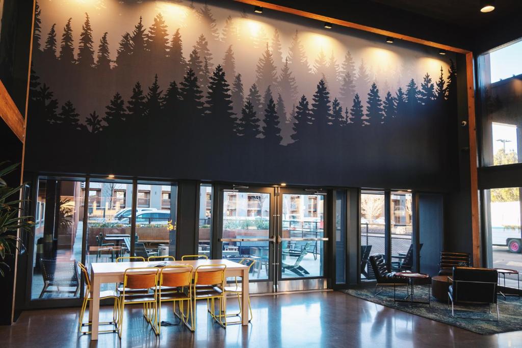 a table and chairs in a restaurant with a mural of trees at Waypoint Hotel in Bend