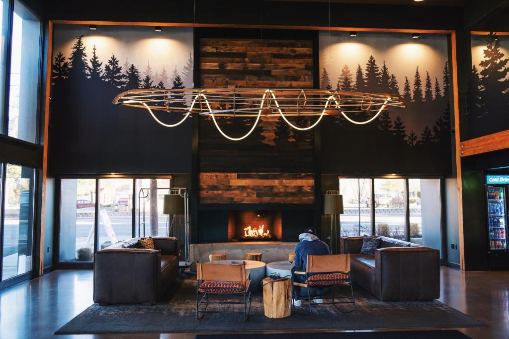 a lobby with a fireplace and chairs and a chandelier at Waypoint Hotel in Bend