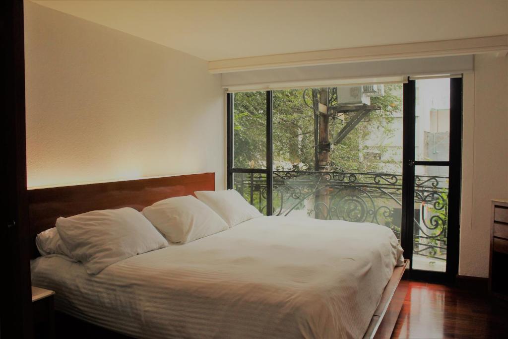 1 dormitorio con cama y ventana grande en Condesa Suites, en Ciudad de México