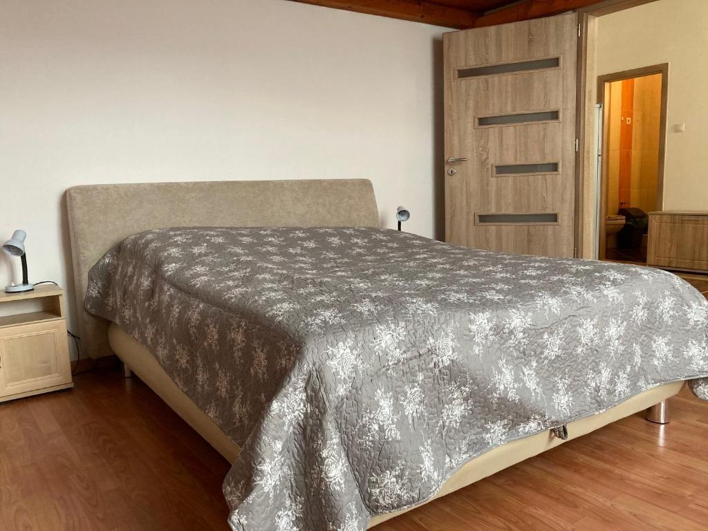 a bedroom with a bed with a gray comforter at Széchenyi Apartman in Eger