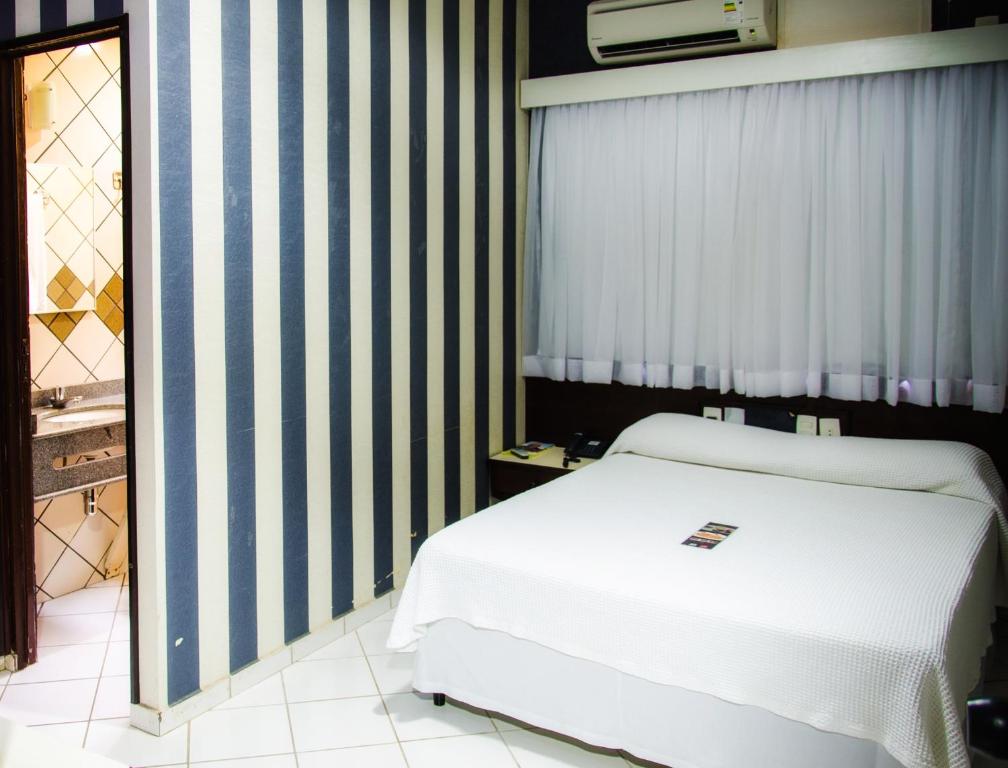 a bedroom with a white bed and striped walls at Pousada dos Girassóis in Palmas