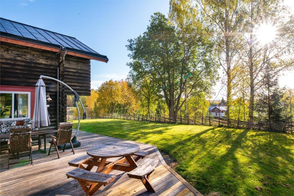 a backyard with a wooden deck and a picnic table at Luxurious Log House - Gränsfors 354 in Bergsjö