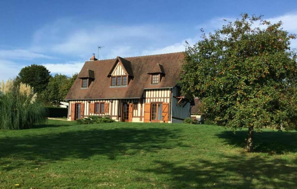 une grande maison brune avec un arbre dans la cour dans l'établissement Relais équestre du Miloir - chambres d'hôtes, à Saint-Martin-de-la-Lieue