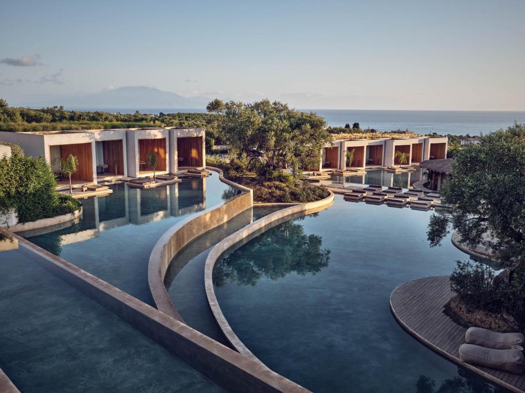 a pool at a resort with the ocean in the background at Olea All Suite Hotel in Tsilivi