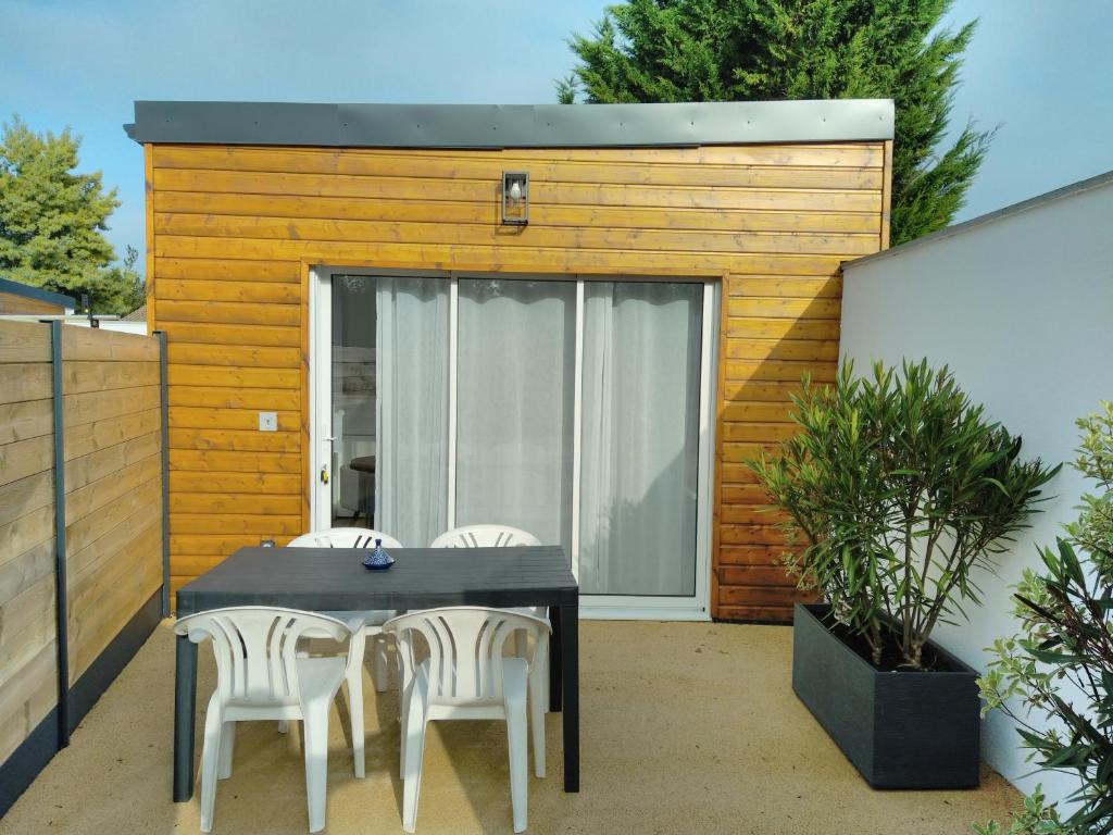 un patio con mesa y sillas frente a un edificio en La Petite Maison Des Marais, en Bourgneuf-en-Retz