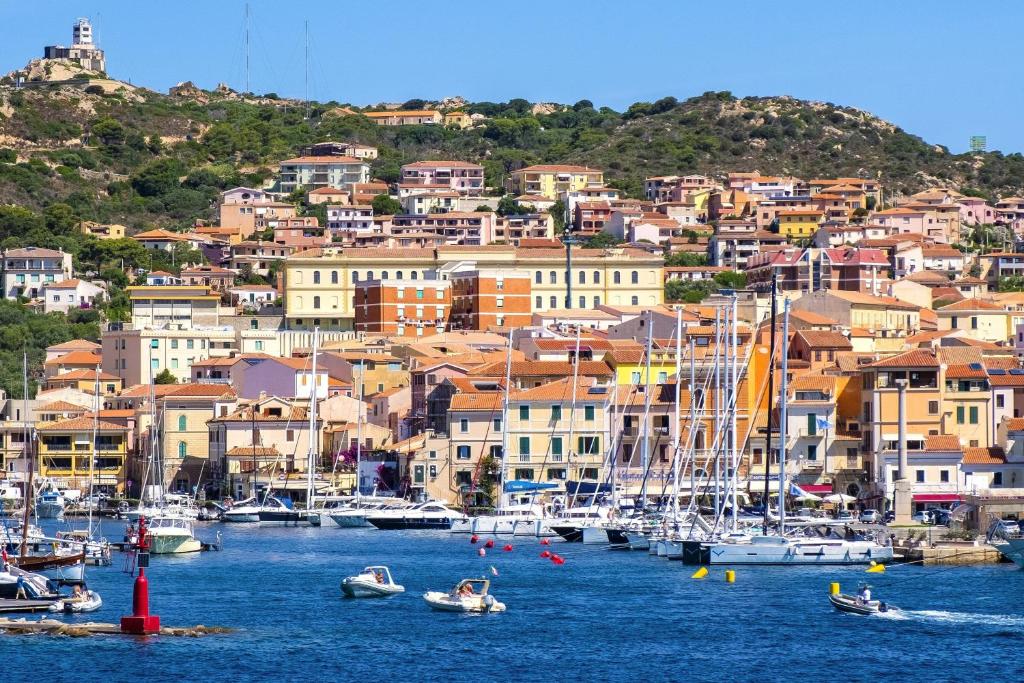 eine Gruppe von Booten, die in einem Hafen mit Gebäuden angedockt sind in der Unterkunft AHR Leonis Residence La Maddalena in La Maddalena