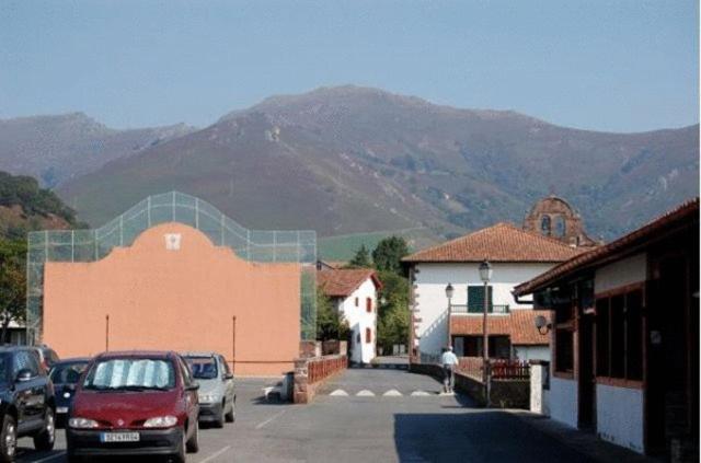 a parking lot with cars parked in front of a mountain at Hotel Restaurant Noblia in Bidarray