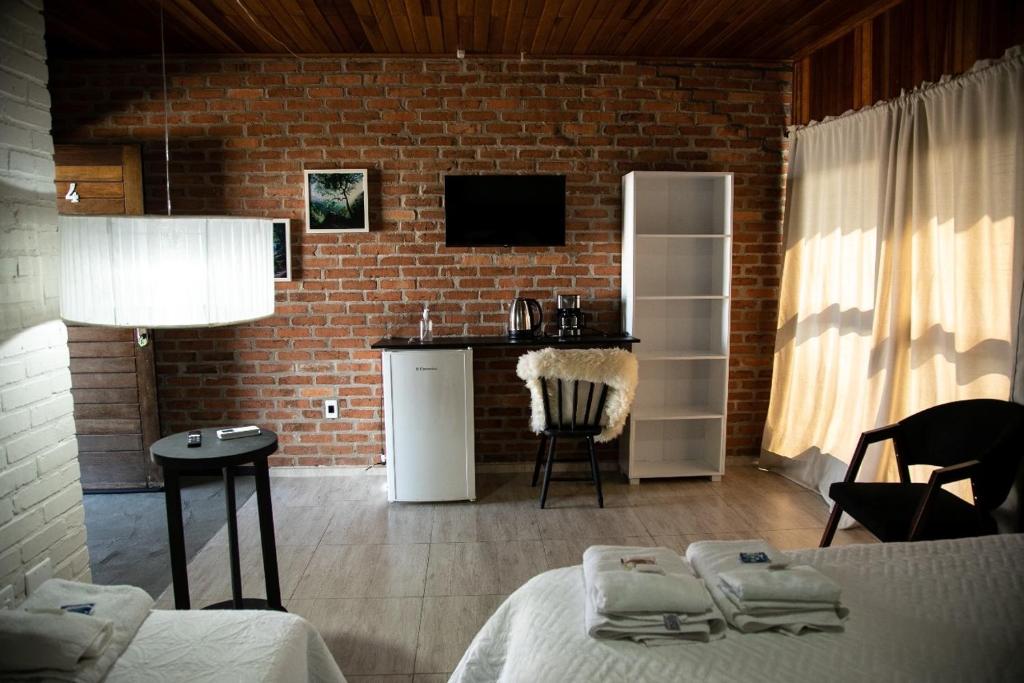 a room with a brick wall and a kitchen with a table at Villagio Santa Tereza in Vacaria