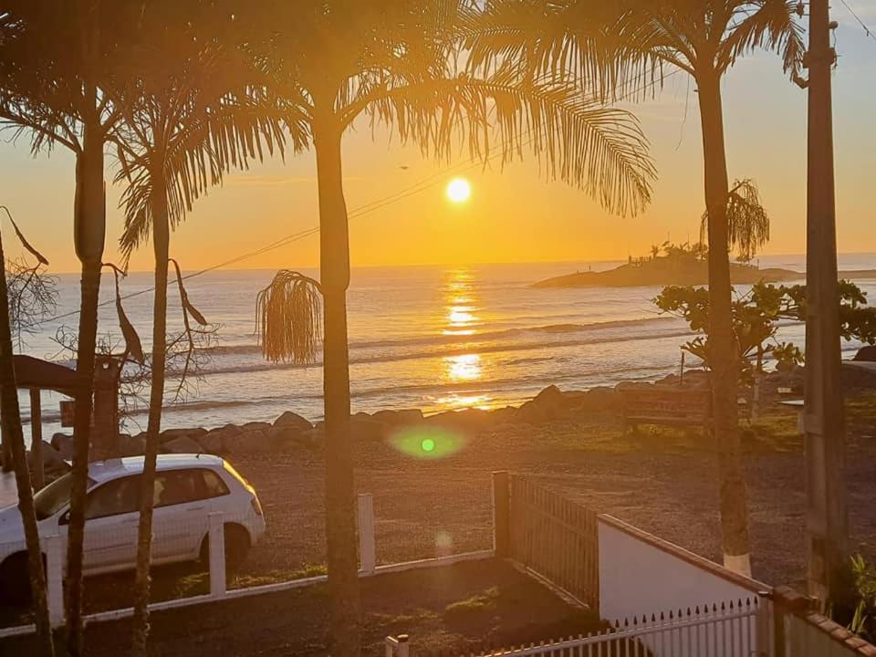 una puesta de sol sobre el océano con un coche aparcado en la playa en Ótima casa beira mar Itapoá - SC, en Itapoa