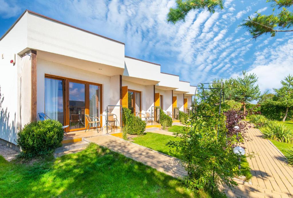 une maison blanche avec un jardin et une pelouse dans l'établissement Oasis, à Gąski