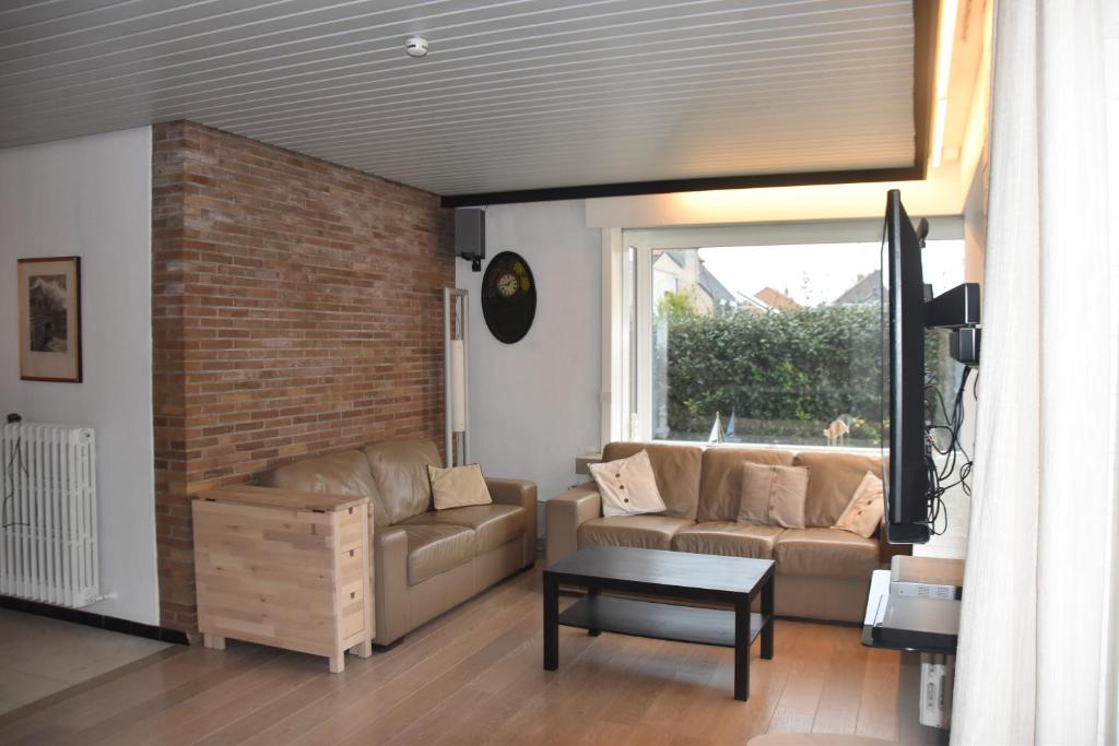 ein Wohnzimmer mit Sofa und Ziegelwand in der Unterkunft 't Calmeyntje in De Panne