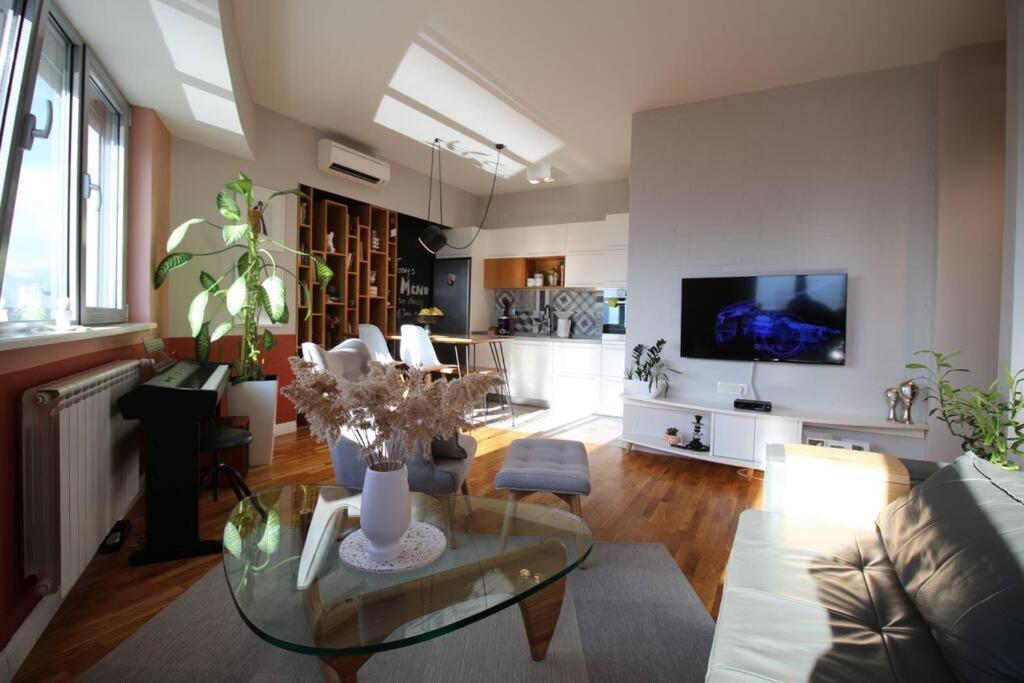 een woonkamer met een glazen tafel en een televisie bij Kristina's Cozy Designer Apartment in Skopje