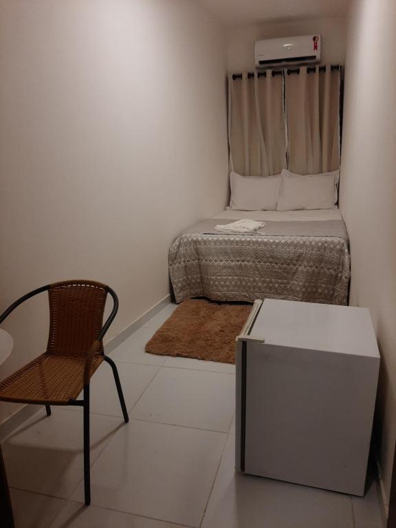 um pequeno quarto com uma cama e uma cadeira em Aconchego de Itapuã em Salvador