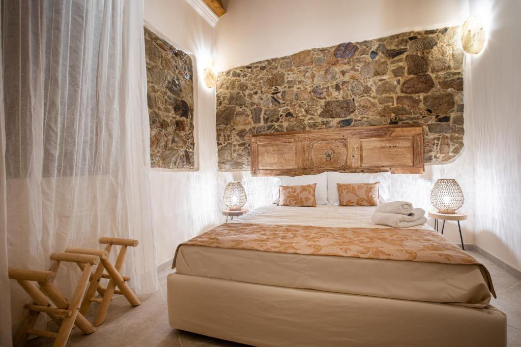 um quarto com uma cama e uma parede de pedra em Moon's Tower suite&rooms em Portoscuso