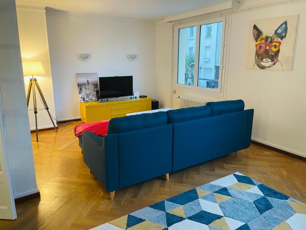 un salon avec un canapé bleu et une télévision dans l'établissement Charmant appartement de cœur de ville - 2 chambres lits Queen size - NETFLIX - WIFI, à Cherbourg en Cotentin