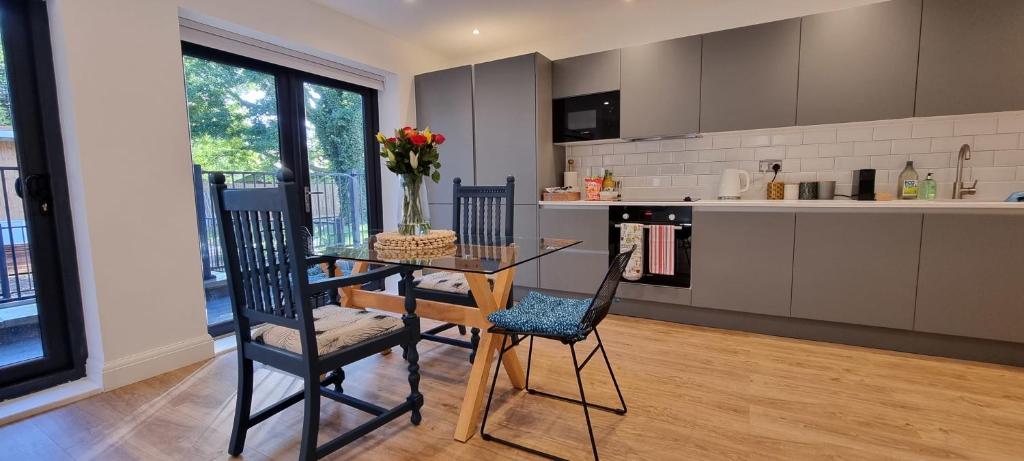 uma cozinha com uma mesa de vidro e 2 cadeiras em Beautiful Apartment Overlooking a Garden em Londres