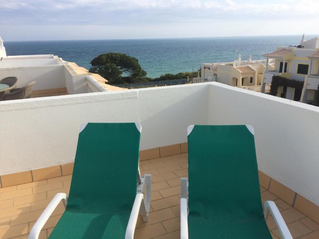 two green chairs on a balcony overlooking the ocean at Seaview Benagil Villa 15 in Benagil