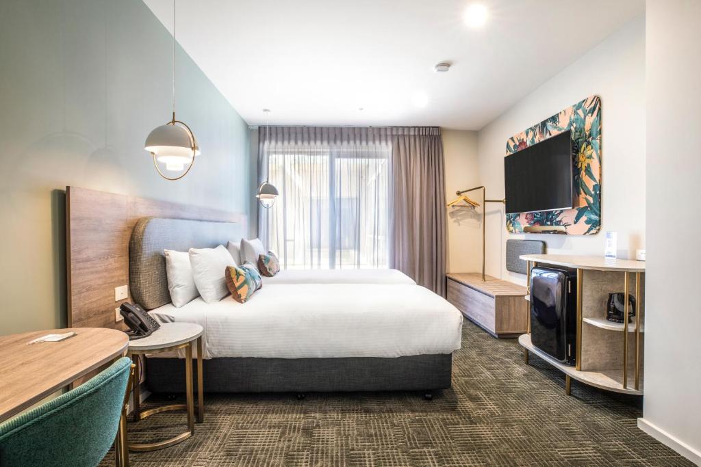 ein Hotelzimmer mit einem Bett und einem Flachbild-TV in der Unterkunft The Sands by Nightcap Plus in Carrum Downs