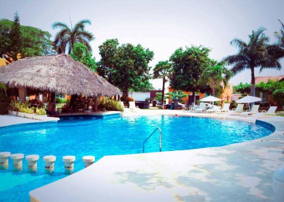 a large blue swimming pool with a straw umbrella at Casa Brisa sol in Acapulco