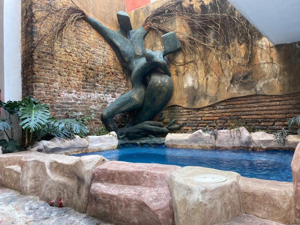 Una statua di una donna in piedi in una fontana di Hotel Raices de Mar a Mazatlán