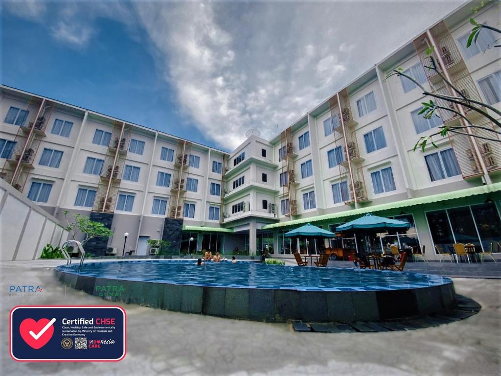 a hotel with a swimming pool in front of a building at Patra Dumai Hotel in Dumai