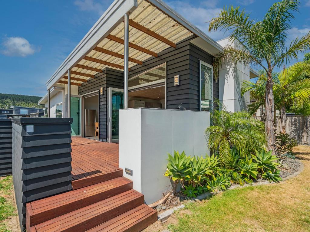 una casa con un ponte di legno davanti di Castaway Bach - Whangamata Holiday Home a Whangamata