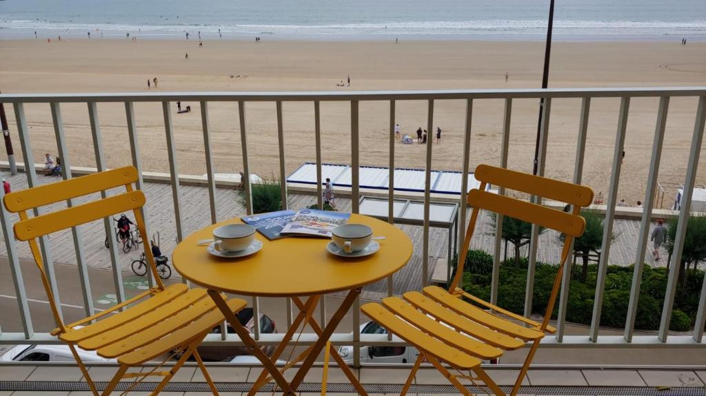 d'une table et de deux chaises sur un balcon avec une plage. dans l'établissement Le Calypso, à Les Sables-dʼOlonne