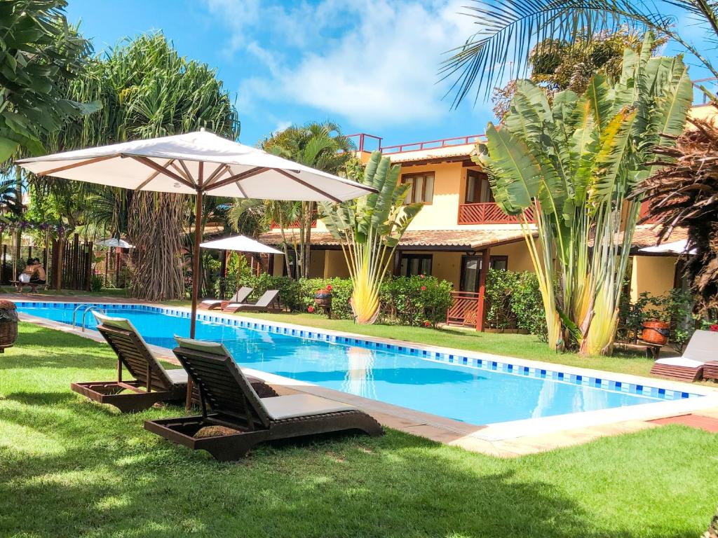 a swimming pool with two chairs and an umbrella at Triplex vista mar no Pipa Beleza in Pipa