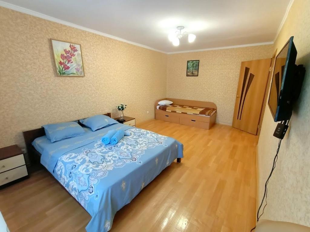 a bedroom with a blue bed and a flat screen tv at 1 комнатные апартаменты на Ауэльбекова 138 in Kokshetau