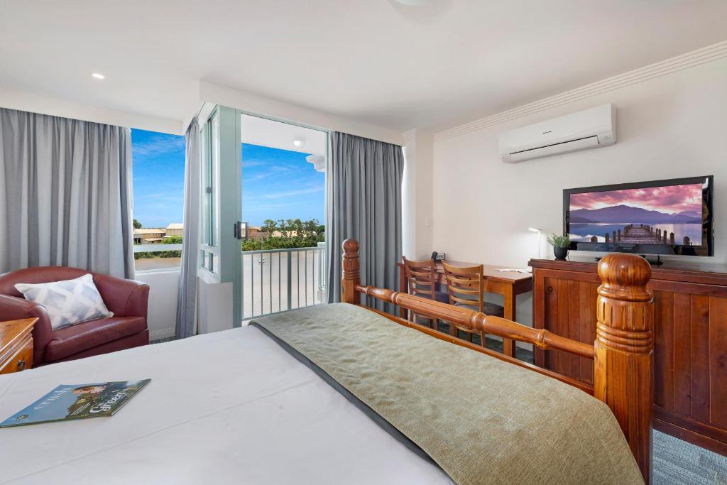 a bedroom with a bed and a desk and a chair at Burnett Riverside Hotel in Bundaberg