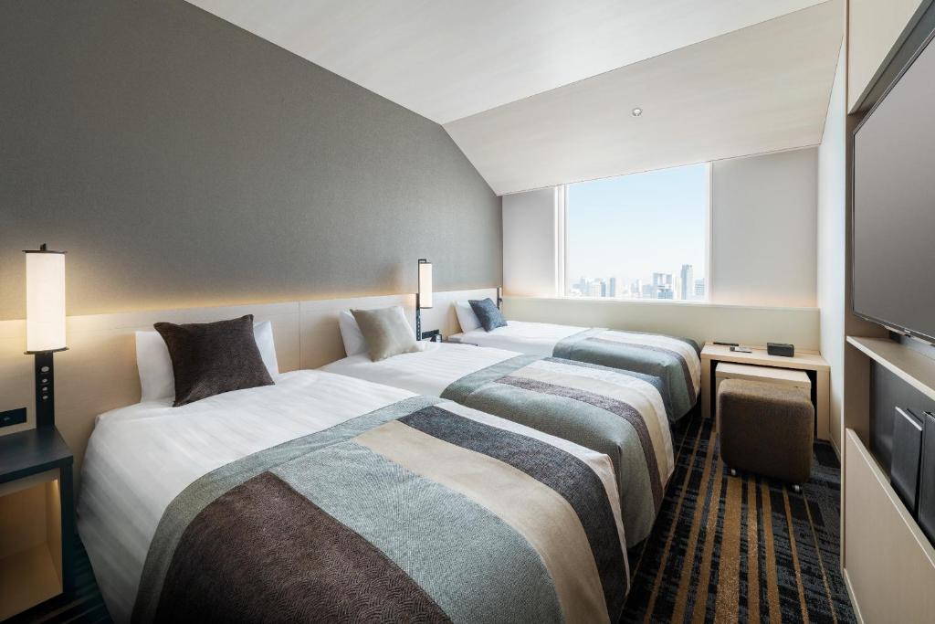 Postel nebo postele na pokoji v ubytování Hotel Hankyu RESPIRE OSAKA