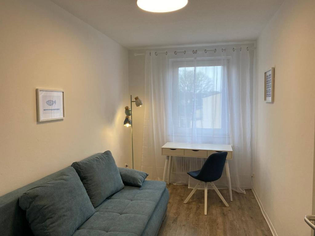 ein Wohnzimmer mit einem Sofa, einem Schreibtisch und einem Fenster in der Unterkunft Blaue Insel neben Hbf-Duisburg in Duisburg