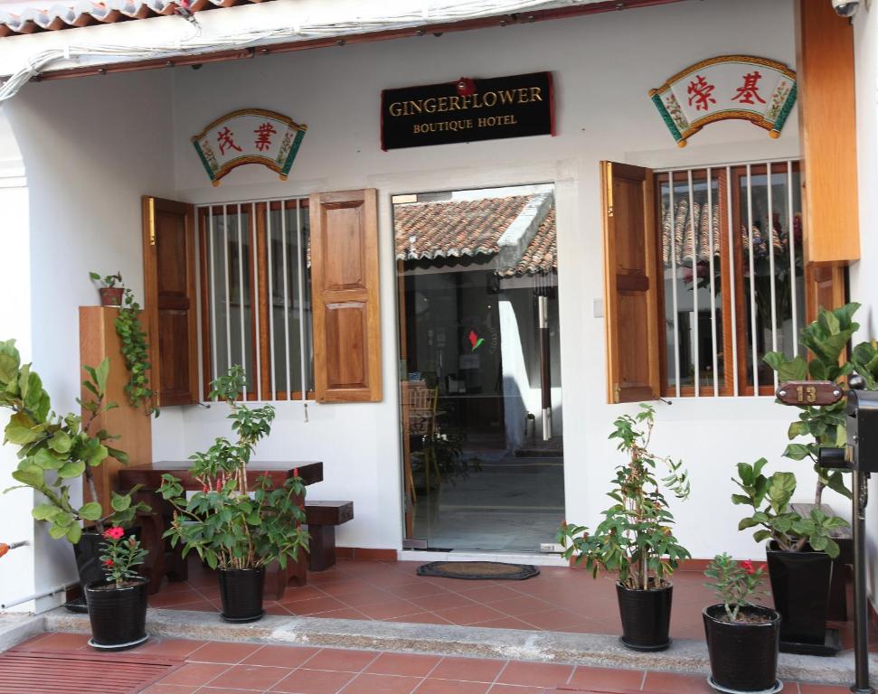 uma porta da frente de uma casa com vasos de plantas em Gingerflower Boutique Hotel em Malaca