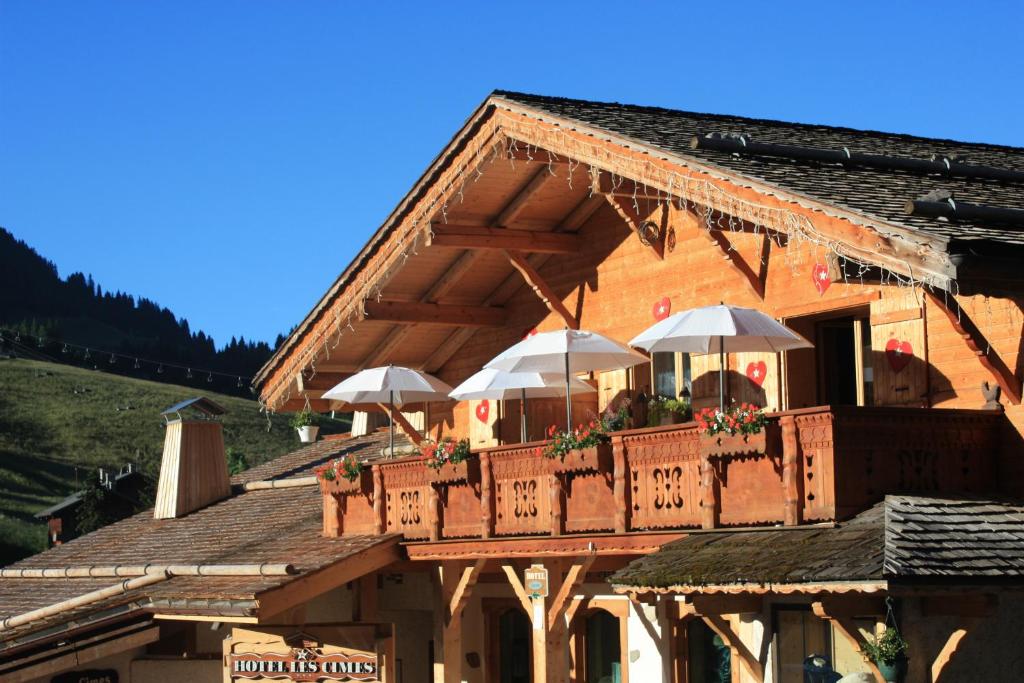 a building with a balcony with umbrellas on it at Chalet-Hôtel Les Cimes in Le Grand-Bornand