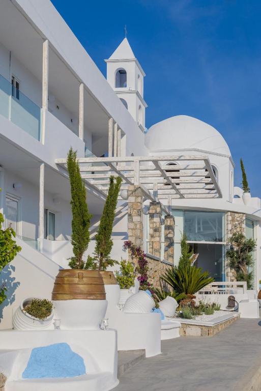 biały budynek z wieżą zegarową w obiekcie Kouros Home & Suites w mieście Faliraki