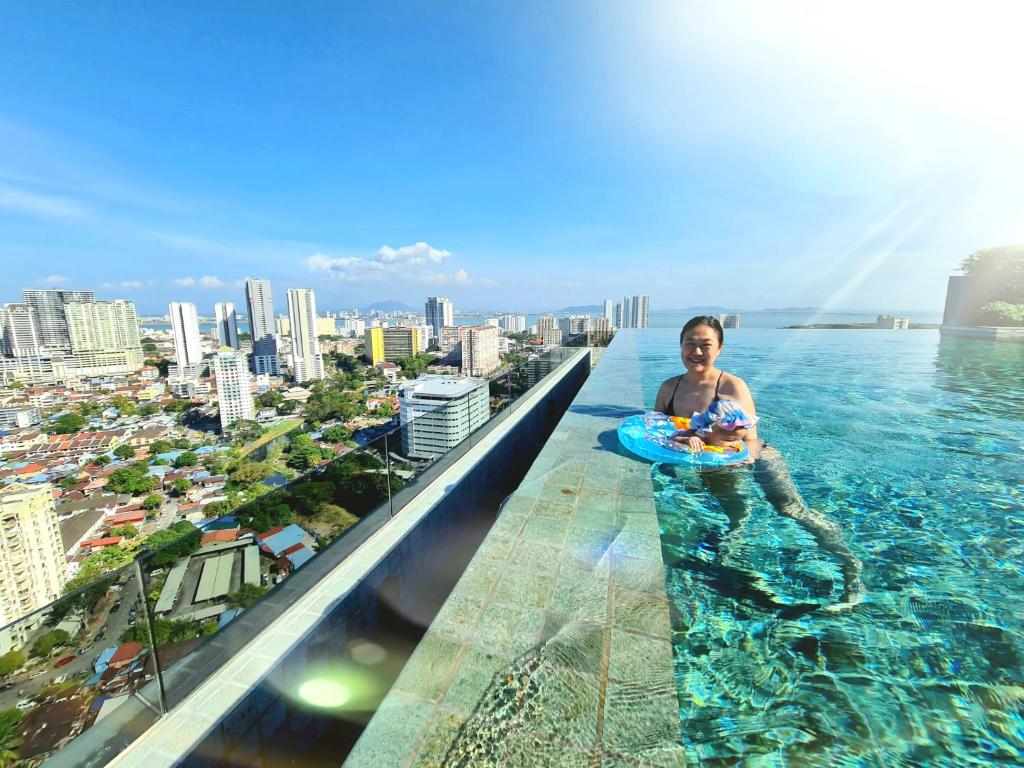 a woman in a infinity pool on the top of a building at Beacon Executive Suites in George Town