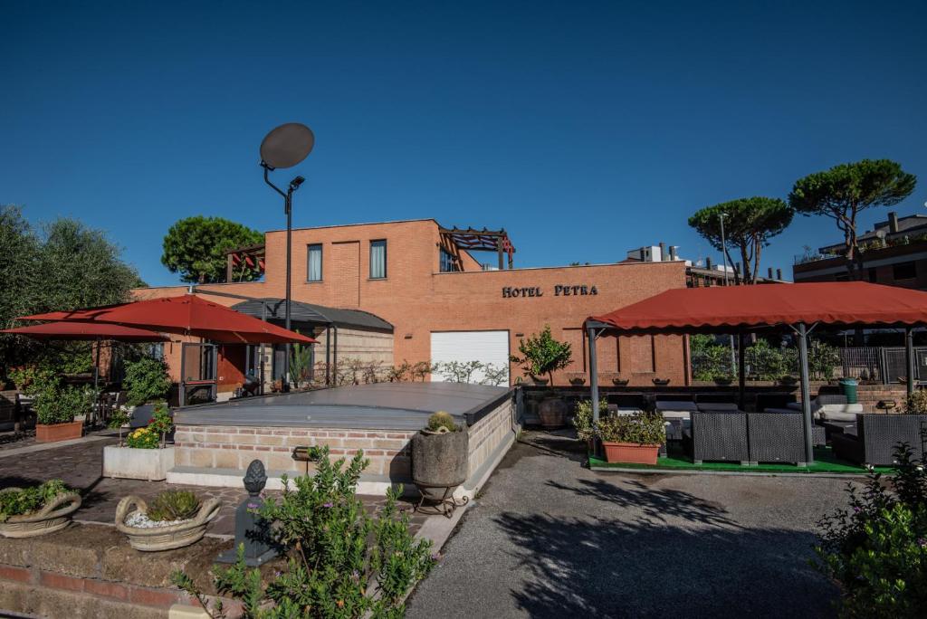 a building with a patio with red umbrellas at Hotel Petra in La Romanina