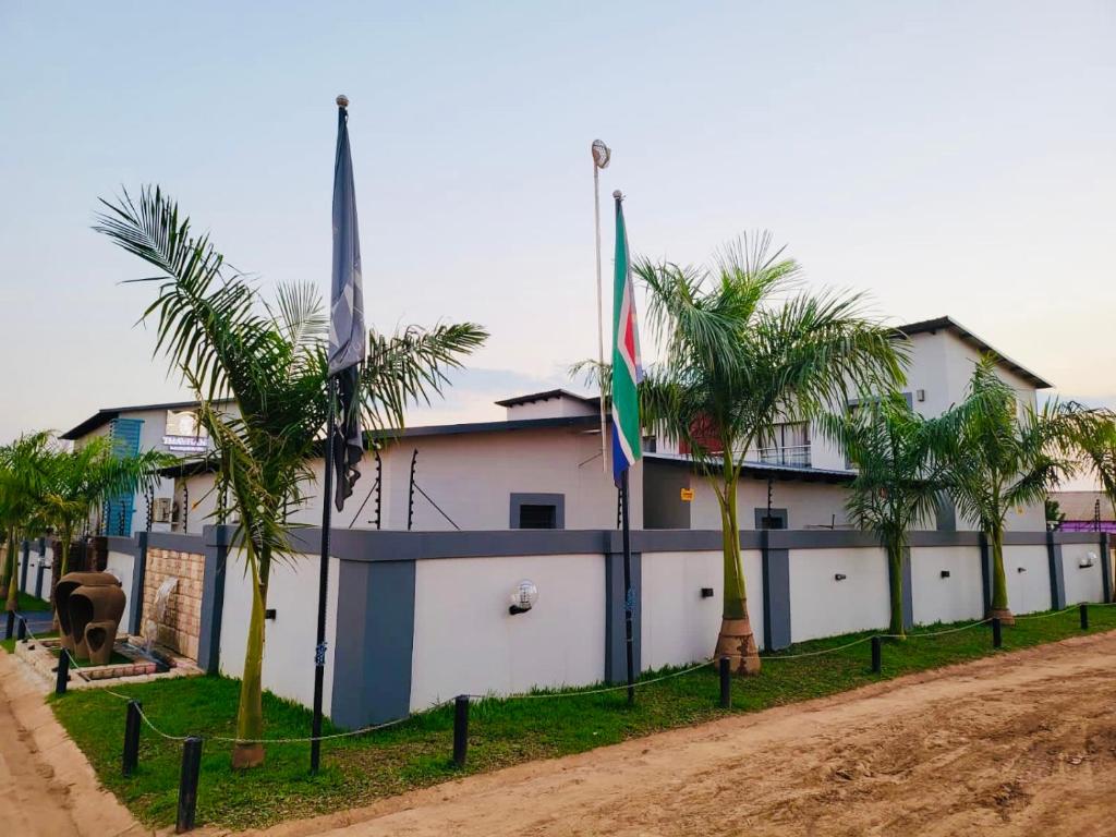 a building with two flags and palm trees in front of it at Thavhani boutique hotel in Thohoyandou