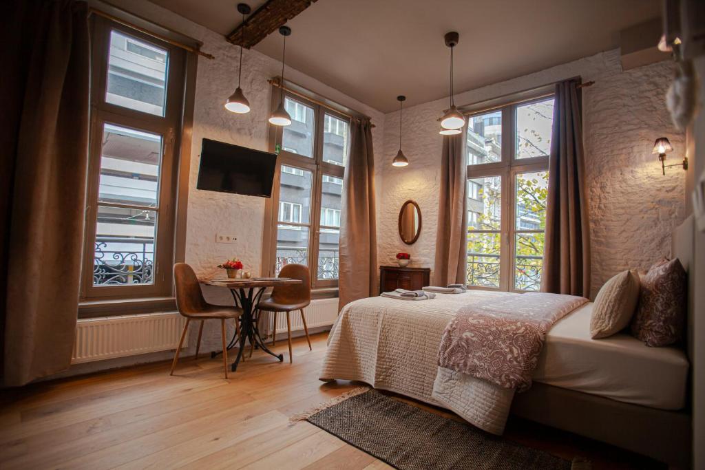 a bedroom with a bed and a table and windows at Luxury Suites Meir in Antwerp
