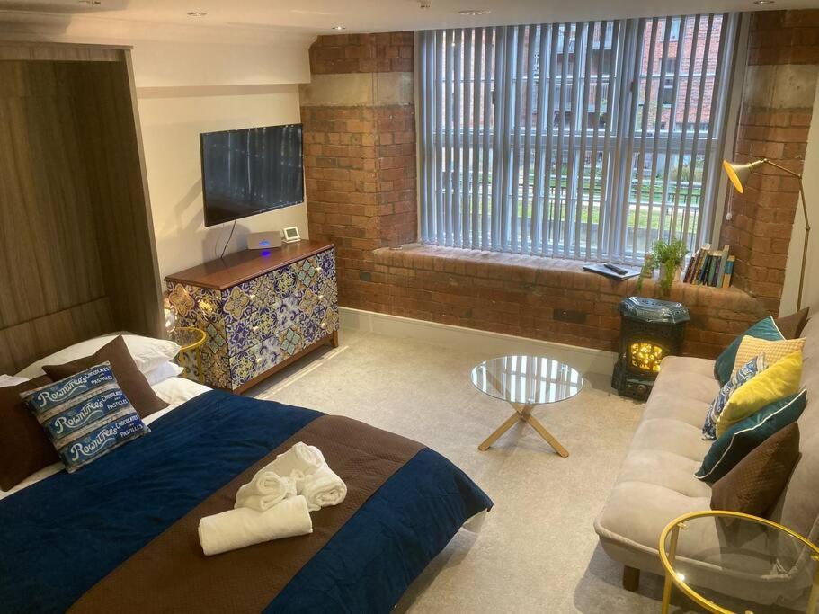 a bedroom with a bed and a couch and a television at 48 Cocoa Suites, York City Centre in York