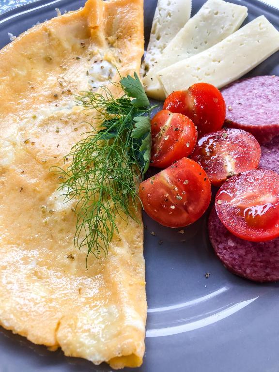 a plate of food with a omelet and tomatoes and cheese at Kisas Loft By Pinch in Pakoštane