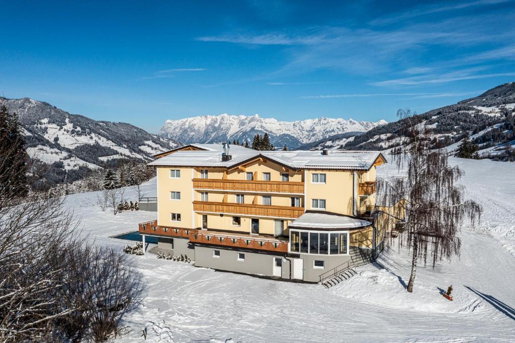 a building in the snow with mountains in the background at Der Alpenblick in Sankt Johann im Pongau