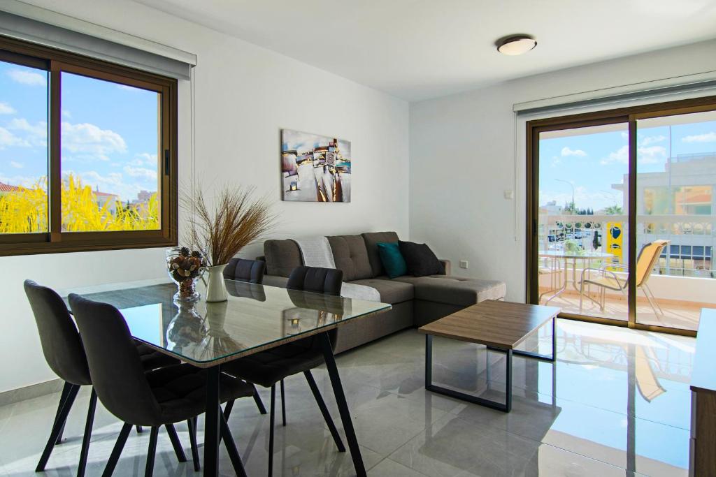 un soggiorno con tavolo in vetro e divano di Phaedrus Living City View Luxury Flat Georgos 203 a Paphos