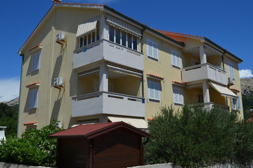 a large apartment building with a dog house in front of it at Apartment Ive in Baška