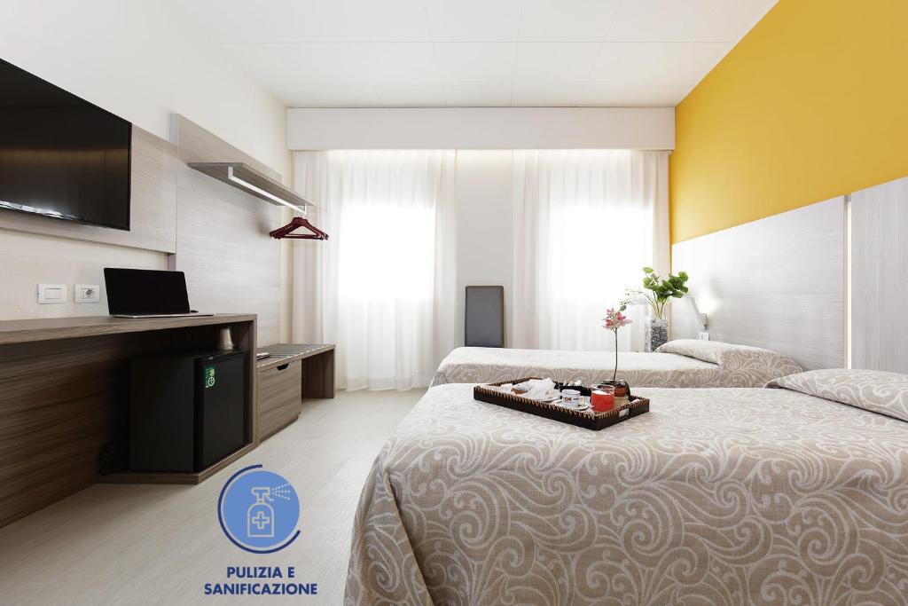 una camera d'albergo con due letti e una televisione di Alfa Fiera Hotel a Vicenza