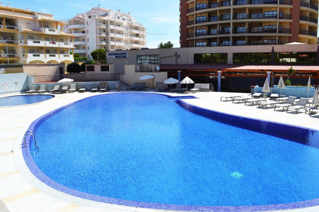 une grande piscine bleue avec des chaises et des bâtiments dans l'établissement S&S Apartment, à Portimão