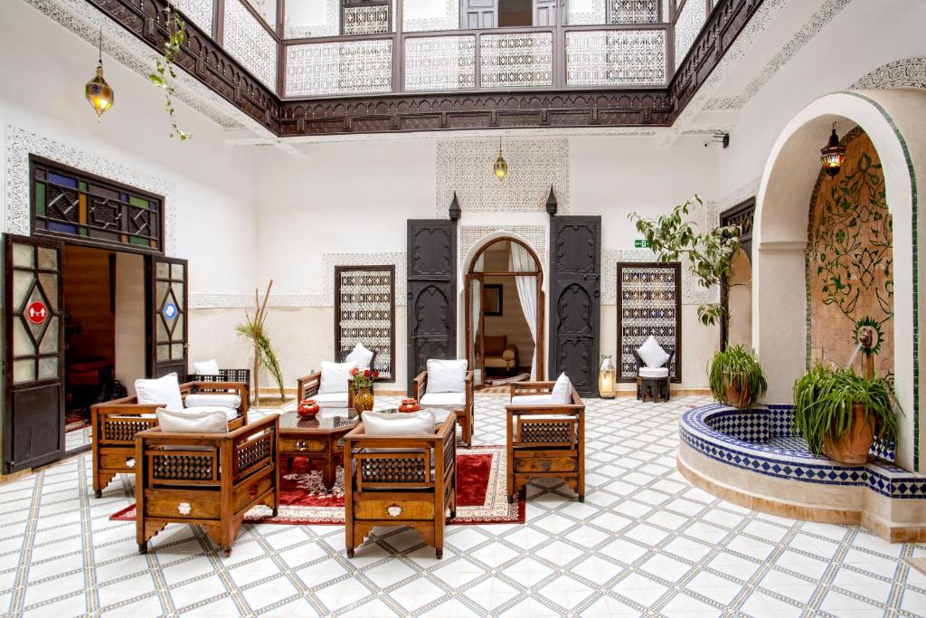 um átrio com cadeiras e mesas num edifício em Riad Al Jana em Marrakech