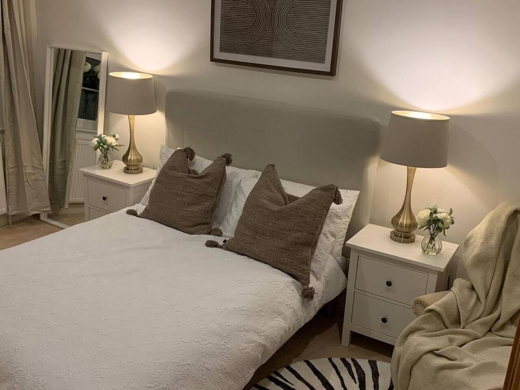 a bedroom with a bed with pillows and two lamps at Cheerful 2-bed cottage with 2 free parking Leeds in Meanwood